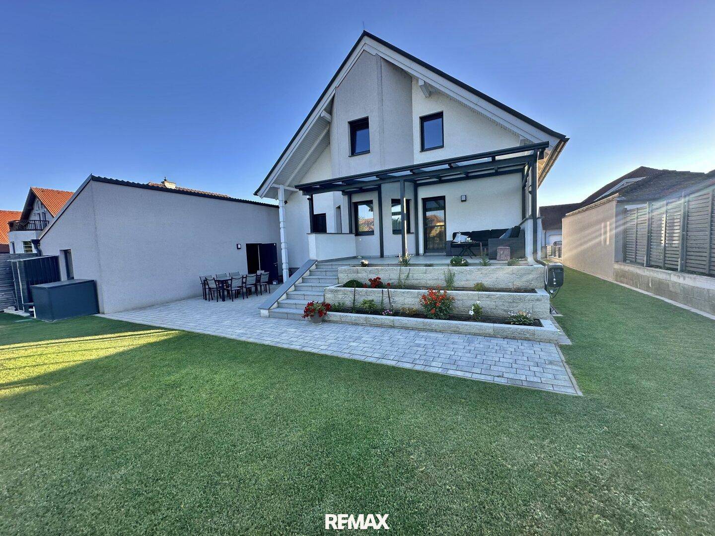 Attraktiver Gartenbereich hinter dem Haus mit Rasenfläche, Terrasse und Blumenbeeten.