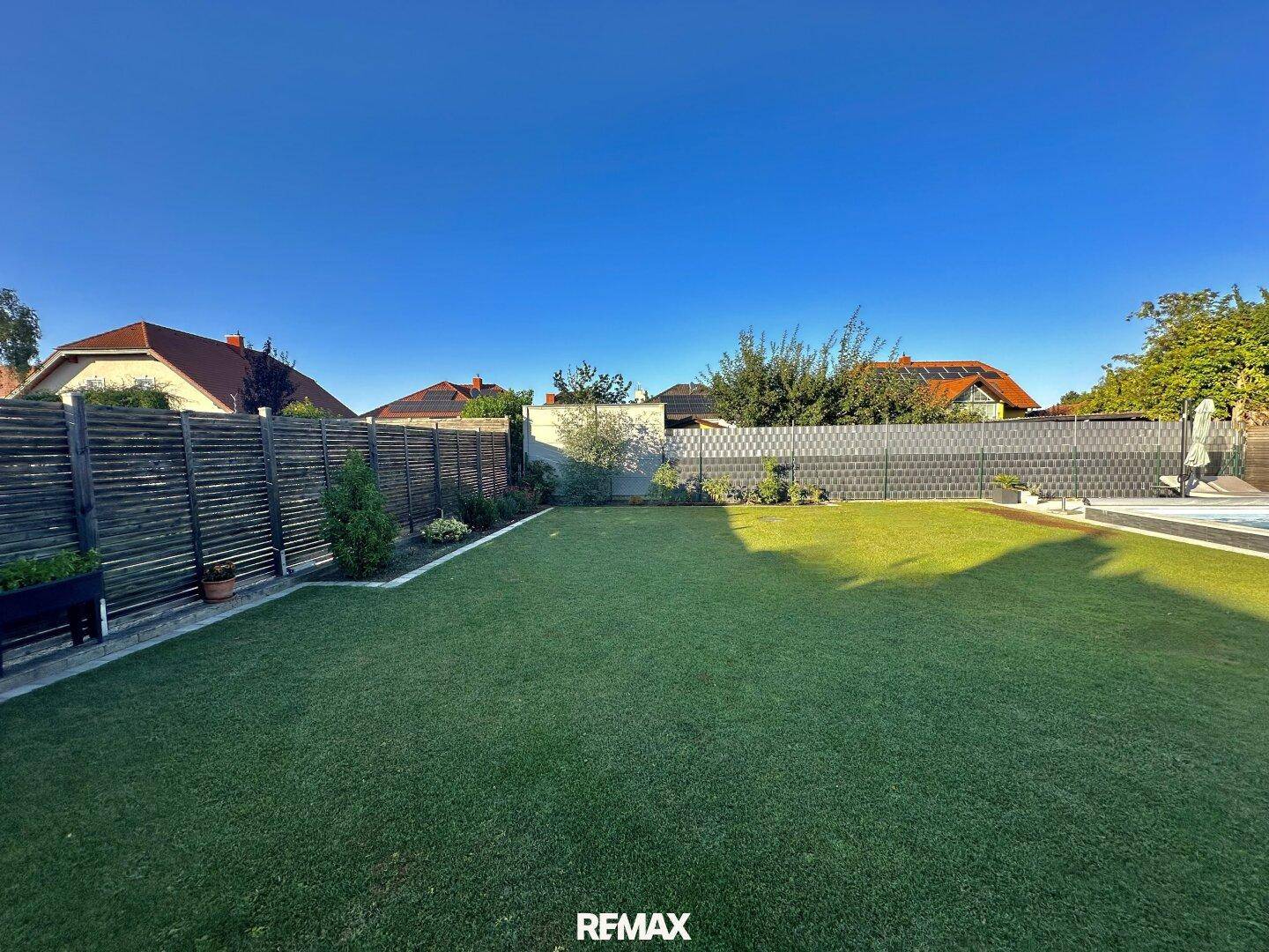 Großer, gepflegter Rasenbereich im Garten, umgeben von modernen Sichtschutzzäunen.