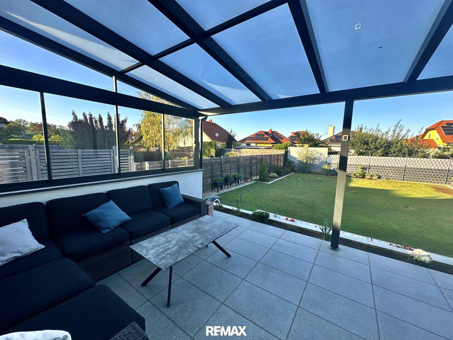 Überdachte Terrasse mit bequemen Lounge-Möbeln und weitem Blick in den grünen Garten.