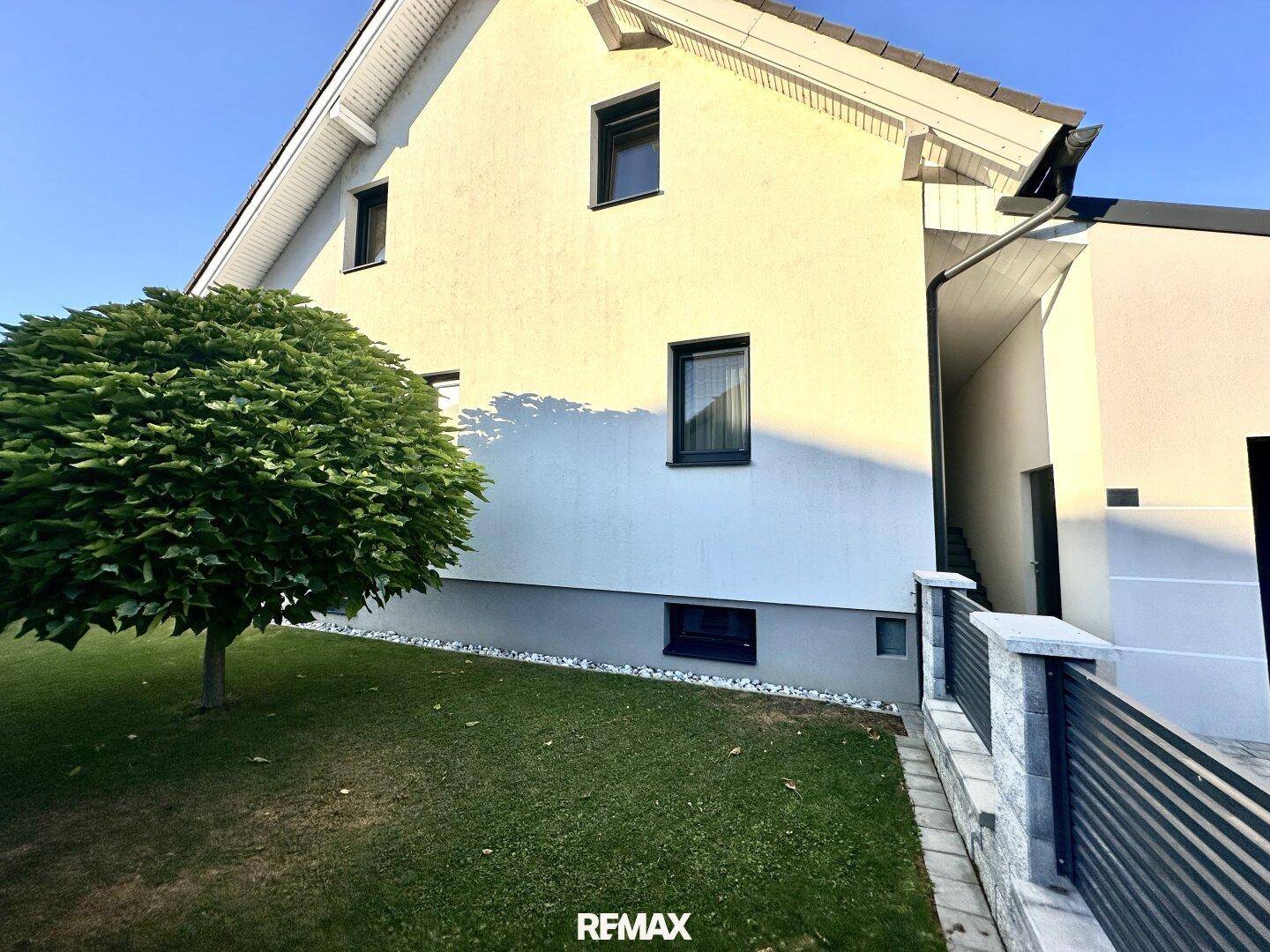 Seitenansicht des Hauses mit einem gepflegten Baum und einem dekorativen Kiesstreifen.