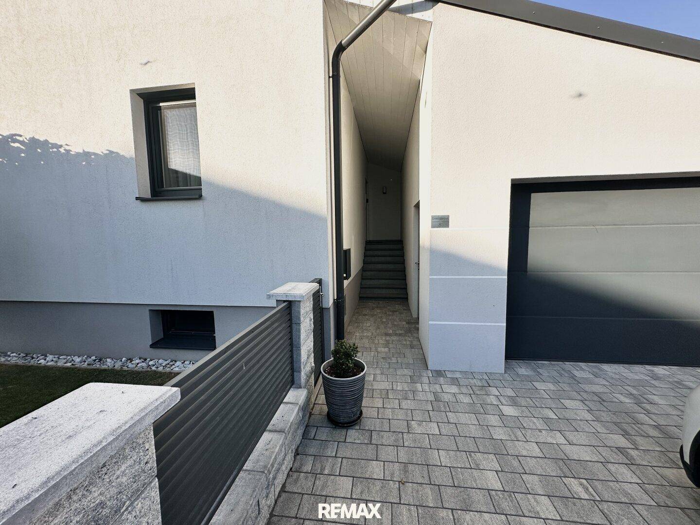 Gepflasterte Auffahrt führt zur Garage und einem seitlichen Eingang mit Treppenaufgang.