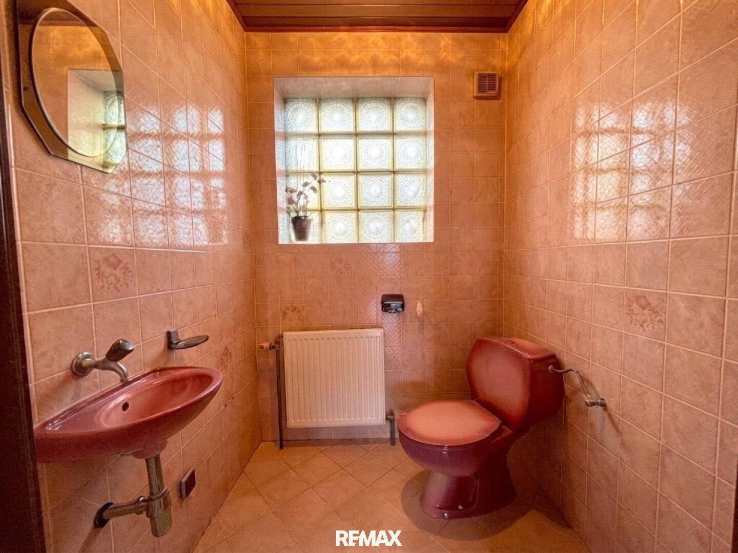 Kleines WC mit rosa Sanitärobjekten und Fliesen im Stil der 80er Jahre.