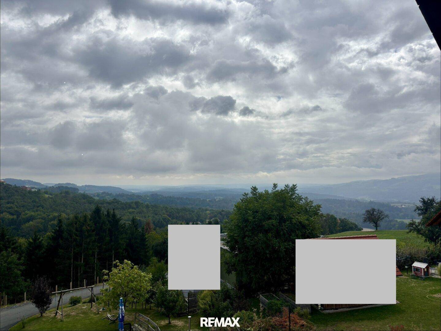 Panoramablick auf die umliegende Natur mit Wäldern und sanften Hügeln an einem bewölkten Tag.