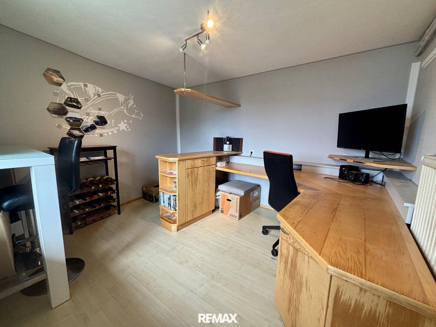 Helles Arbeitszimmer mit Holzschreibtisch, Regalen und Blick auf die umliegende Landschaft.