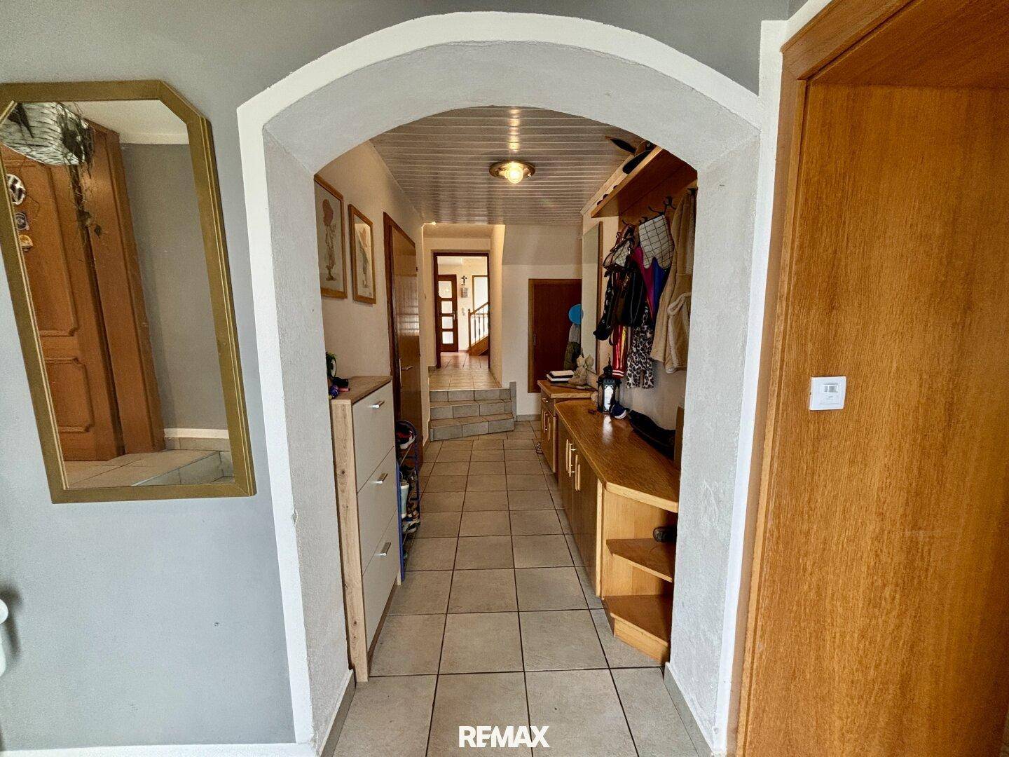 Gemütlicher Eingangsbereich mit Fliesenboden, Holzdecke und Garderobe, der zu weiteren Räumen führt.