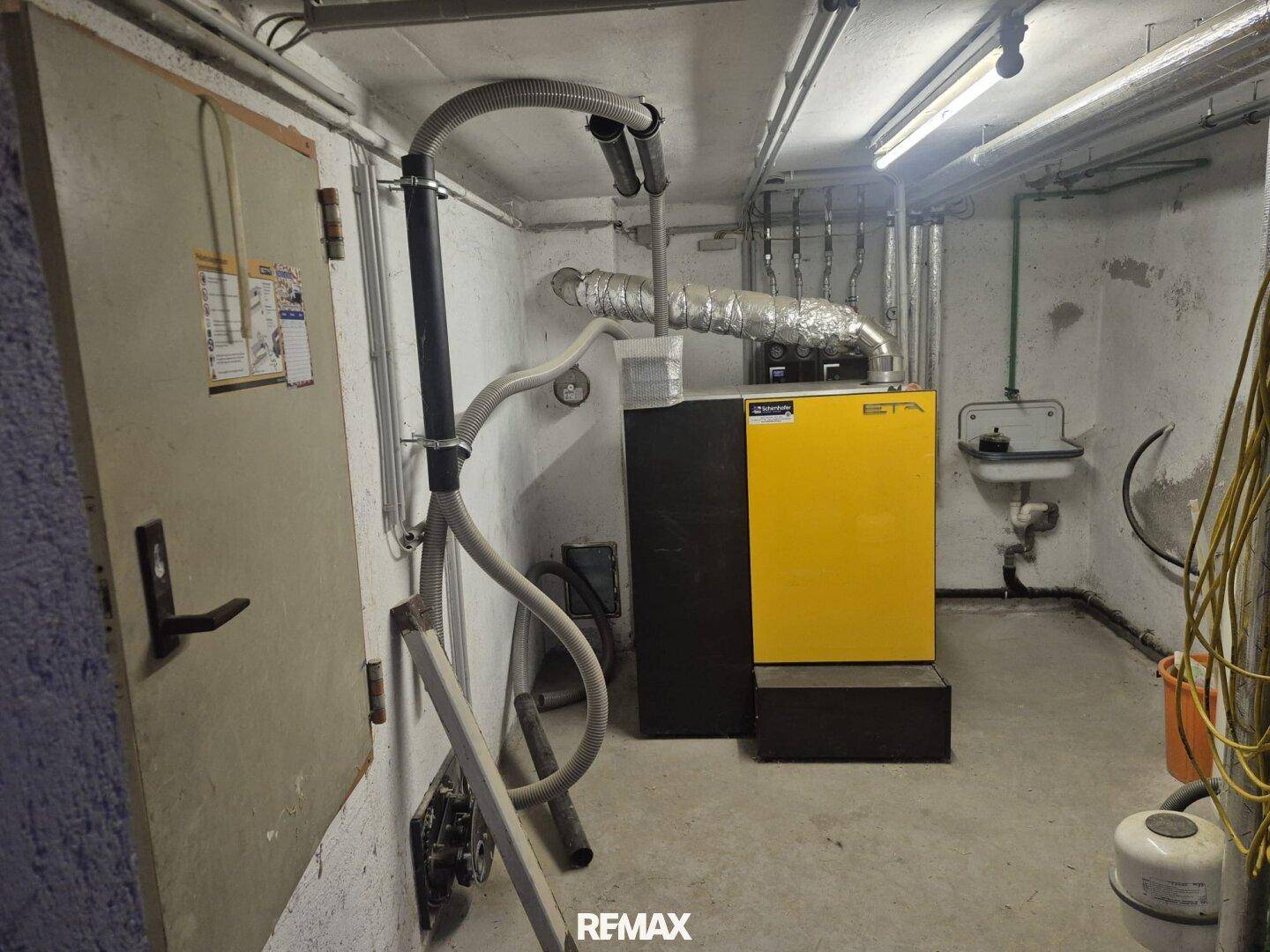 Heizungsraum im Keller mit großem Heizkessel und sichtbaren Installationen.