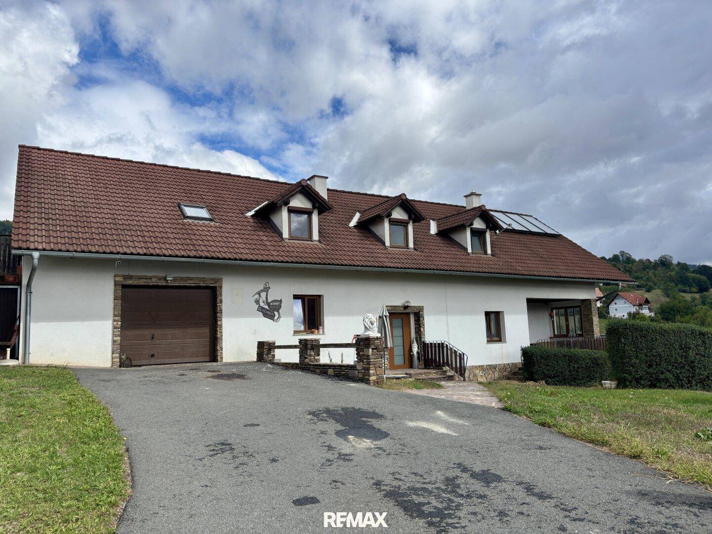 Ansicht des Einfamilienhauses mit Garage und gepflegter Auffahrt unter bewölktem Himmel.