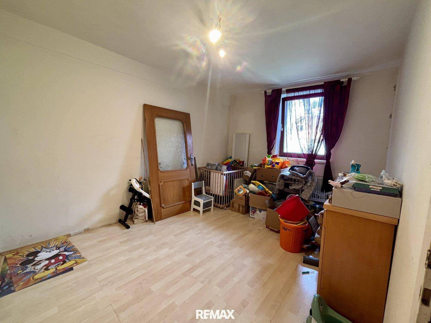 Schlafzimmer mit Laminatboden und Fenster, das viel Tageslicht hereinlässt.