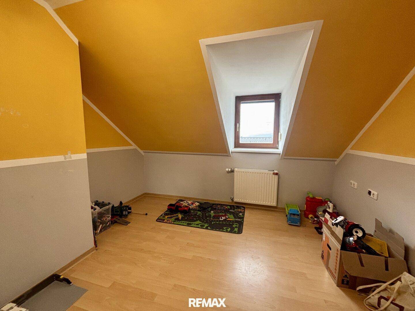 Kinderzimmer im Dachgeschoss mit Laminatboden und farbenfroher Wandgestaltung.
