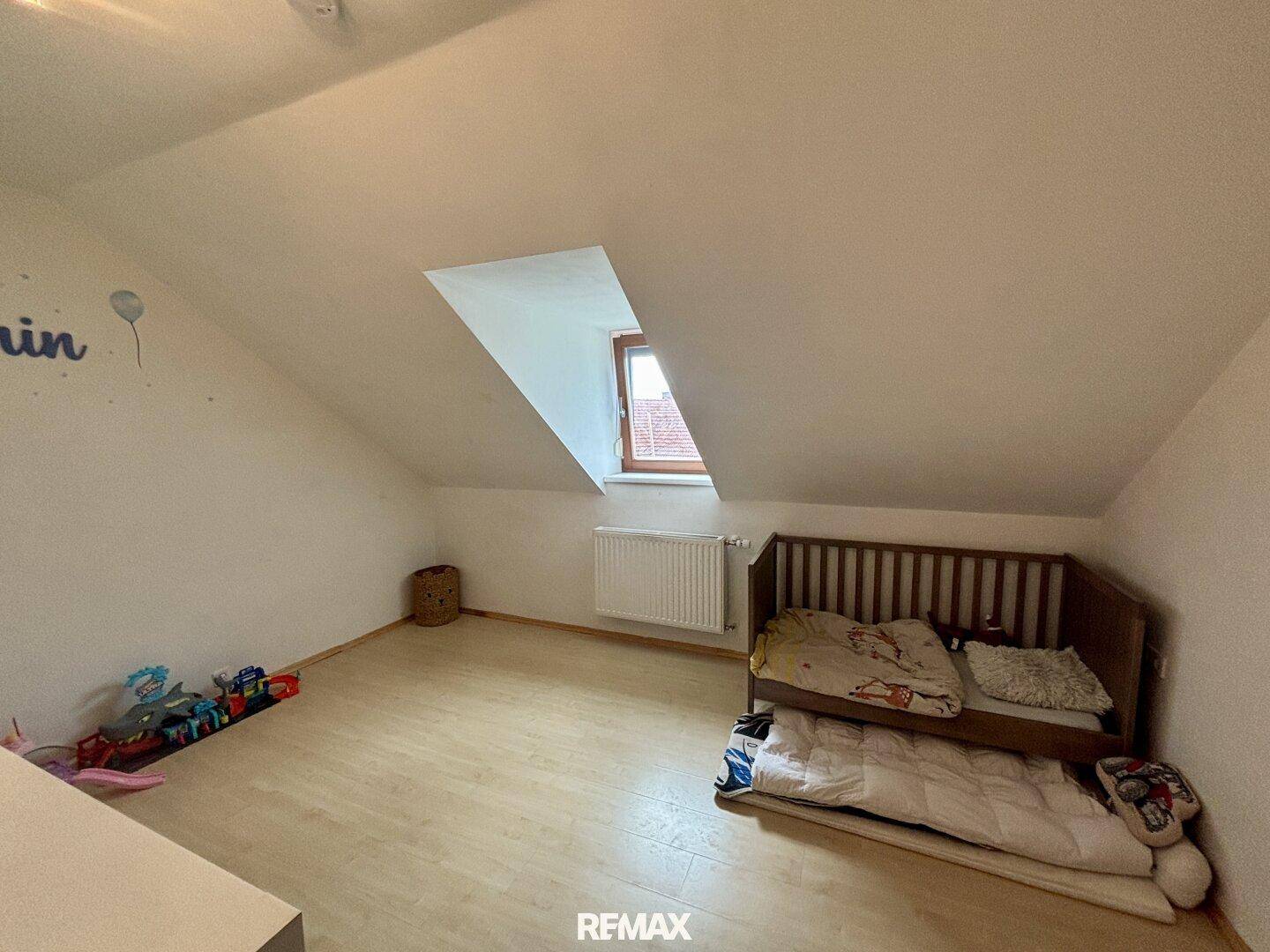 Helles Kinderzimmer im Dachgeschoss mit Laminatboden und Dachfenster.