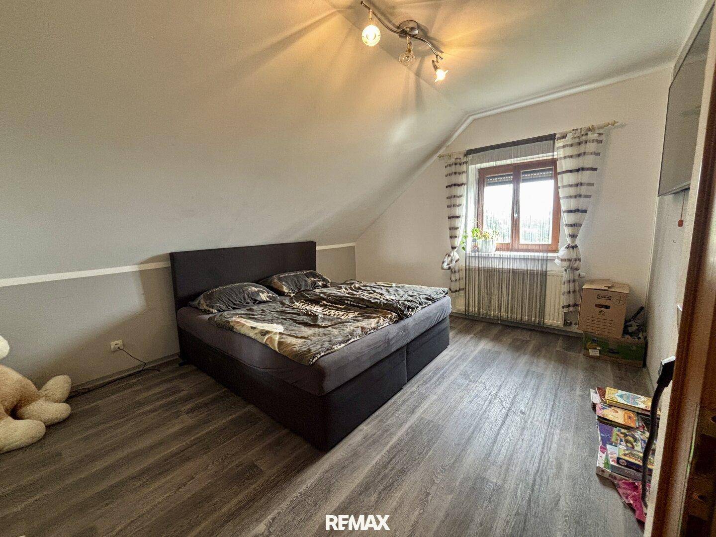 Schlafzimmer im Dachgeschoss mit Doppelbett, Laminatboden und Fenster.