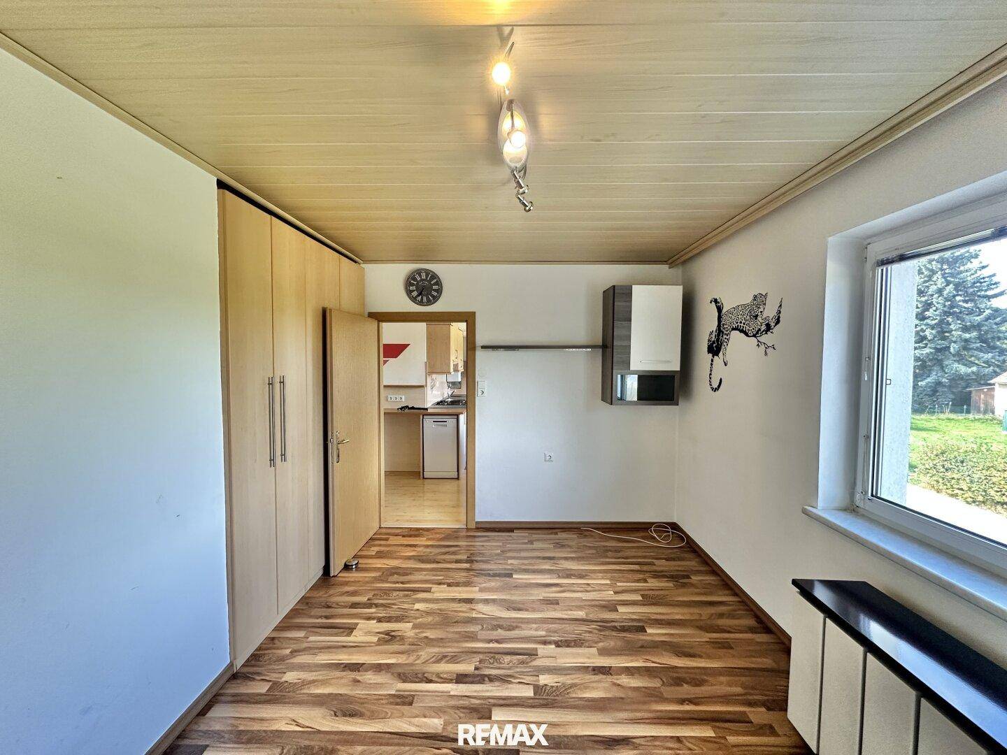Geräumiges Zimmer mit Laminatboden und Zugang zu einem weiteren Wohnbereich.