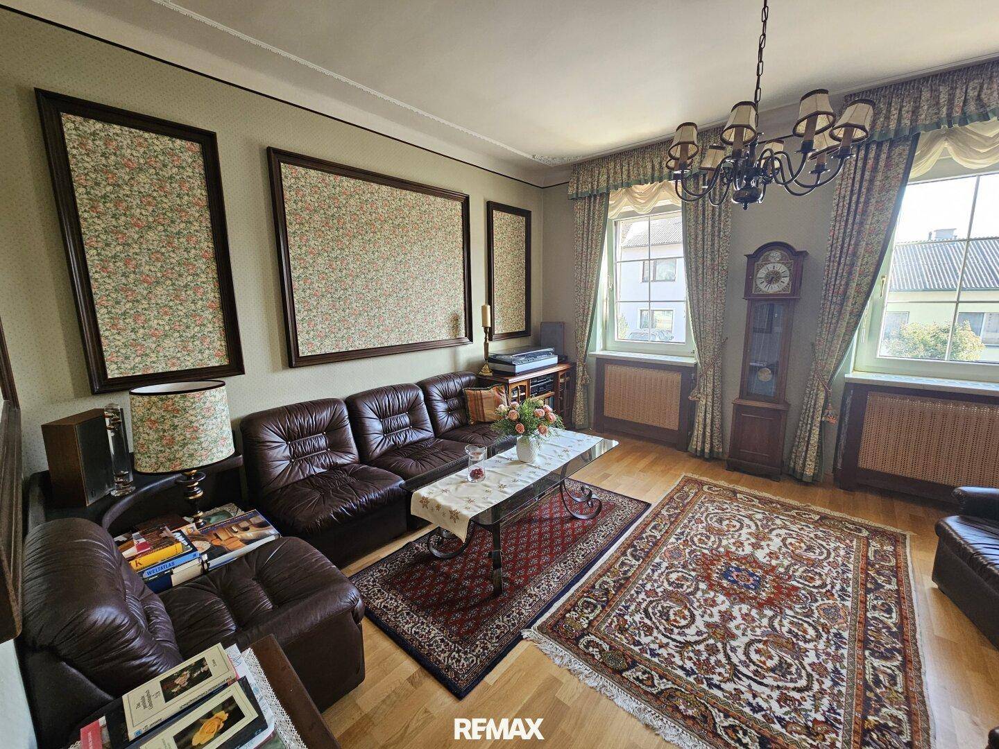 Gemütliches Wohnzimmer mit Ledersofas, Holzboden und großen Fenstern, die viel Licht hereinlassen.