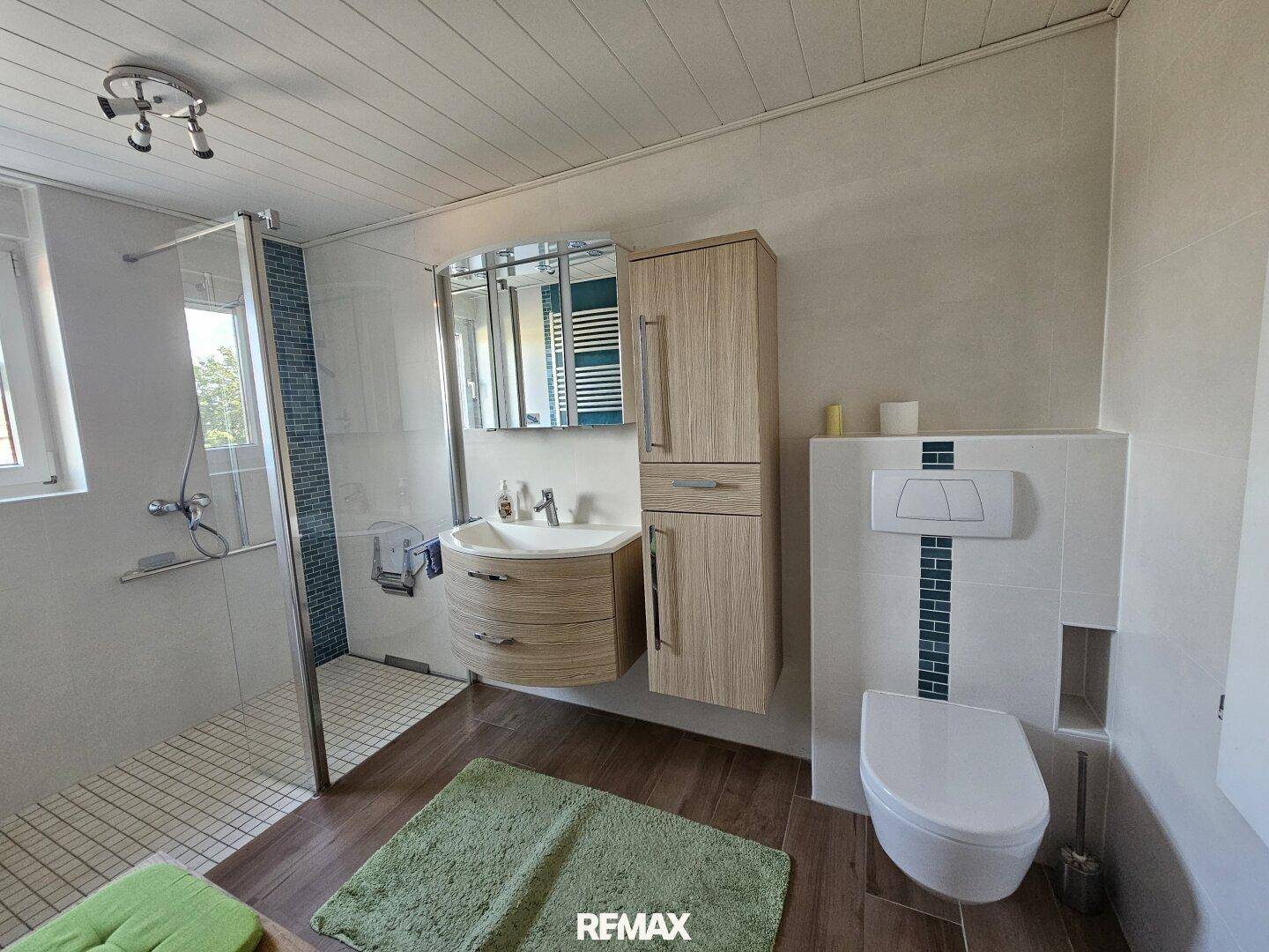 Helles Badezimmer mit Dusche, wandhängendem WC und modernem Waschtisch.
