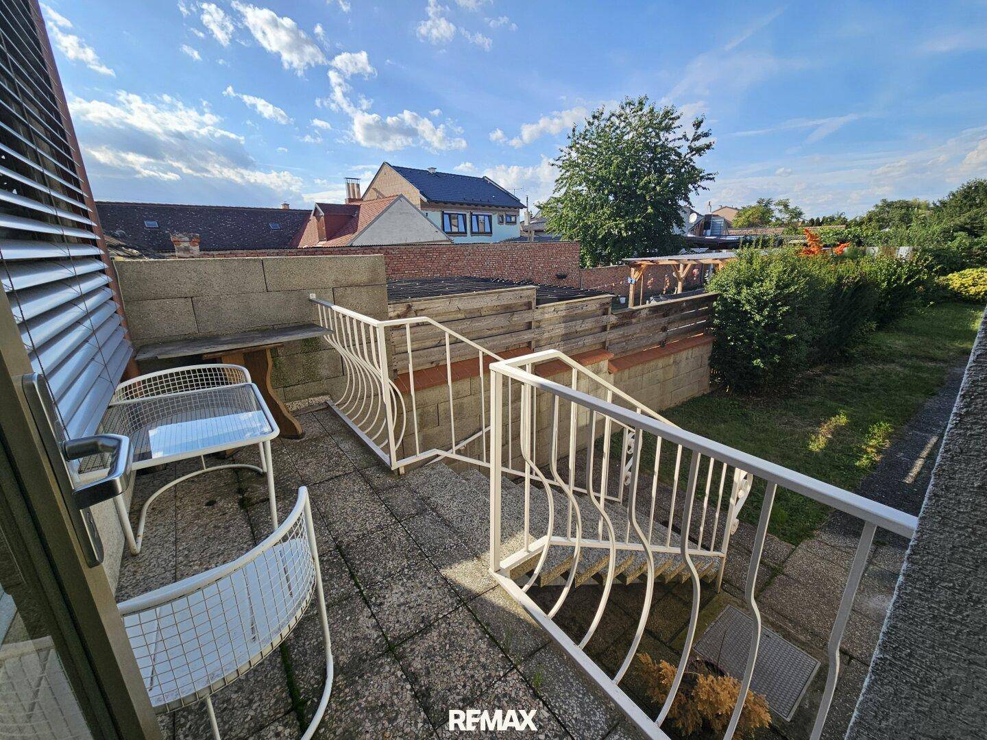 Gedeckte Terrasse mit Sitzgelegenheiten und Blick auf den Garten und die Umgebung.