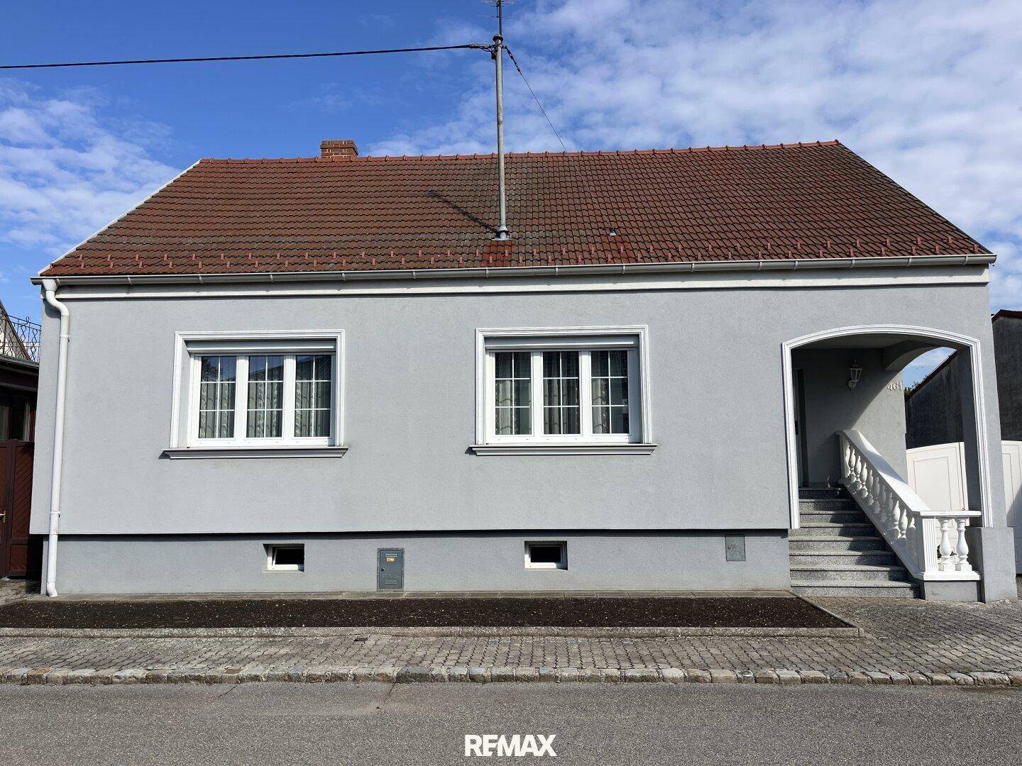 Hausfassade mit schlichter Gestaltung und vorbereitetem Bereich für zukünftige Bepflanzung.