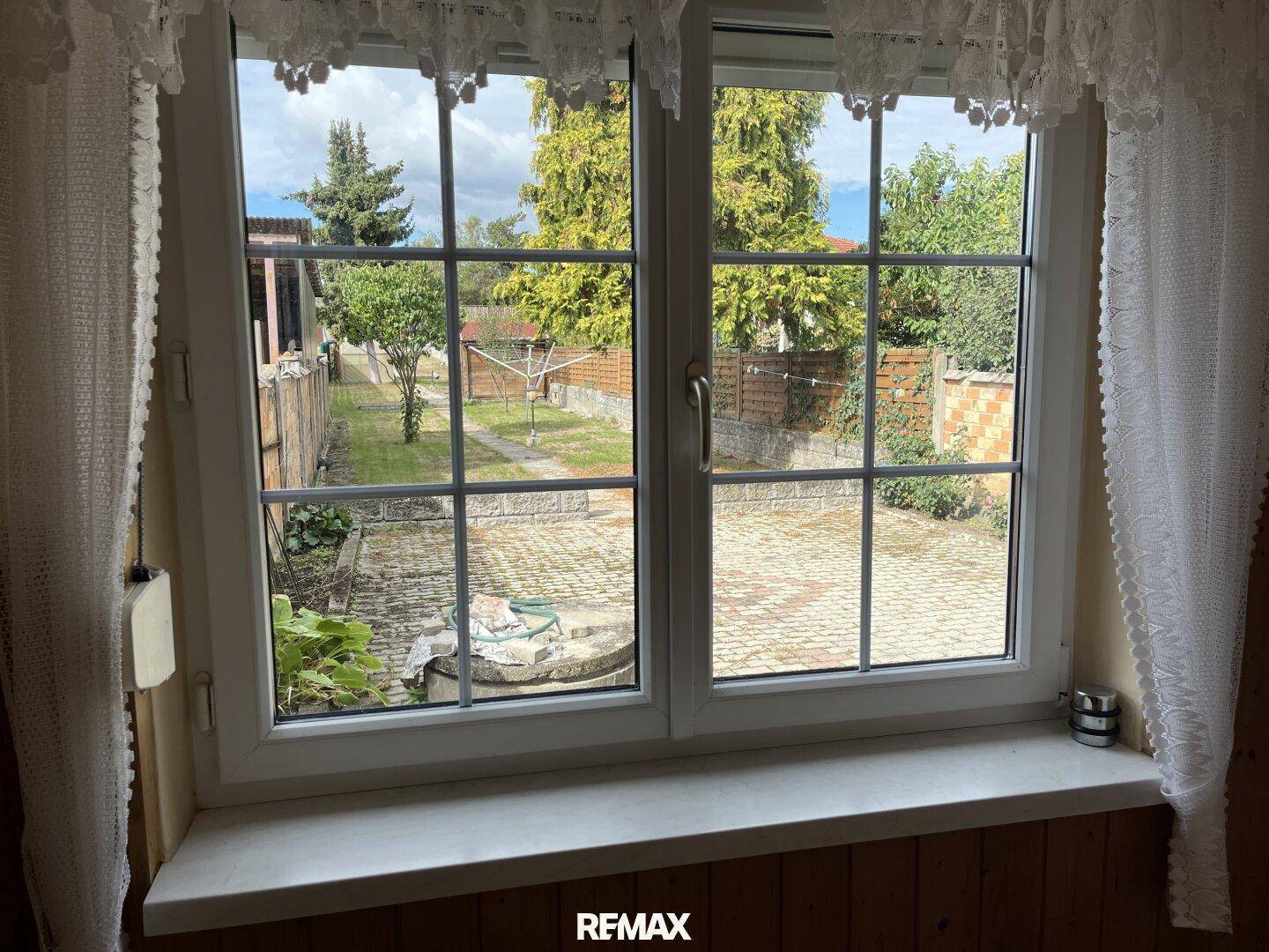 Fenster mit Blick auf den gepflegten Garten und den Außenbereich des Hauses.