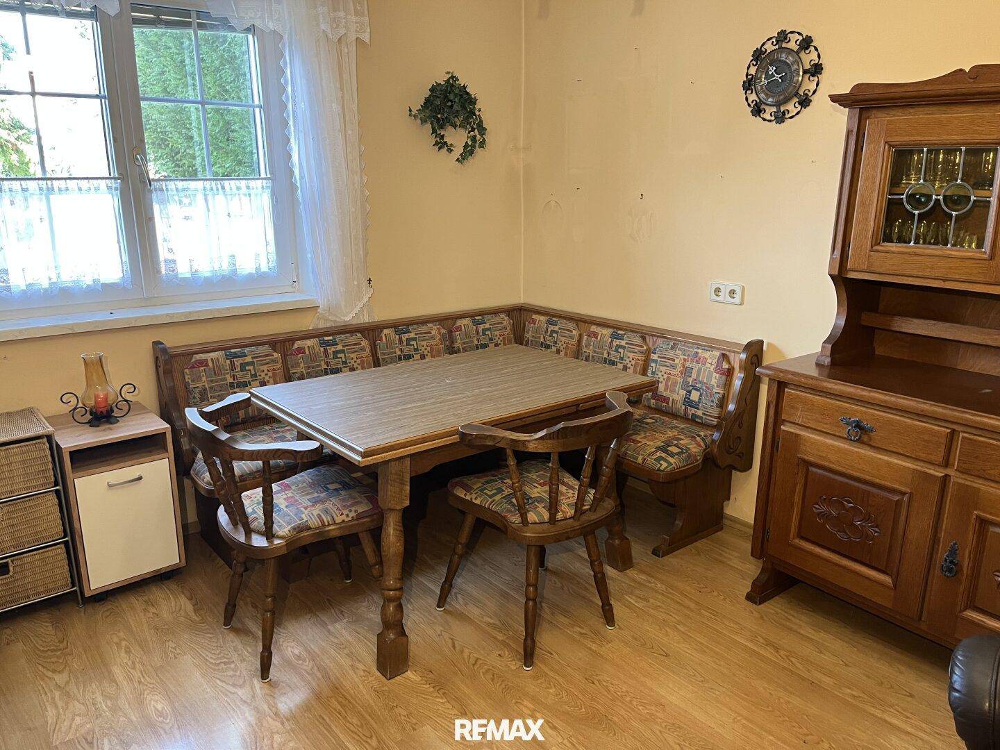 Gemütlicher Essbereich mit Eckbank, Holztisch und traditionellen Holzmöbeln am Fenster.