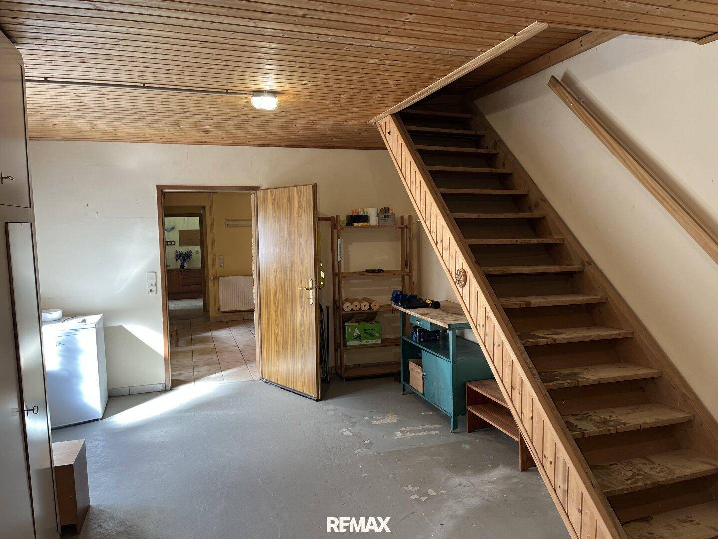 Kellerraum mit Holztreppe, Holzdecke und Stauraum, der zu weiteren Räumen führt.