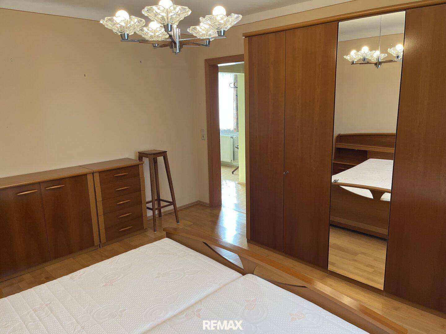 Schlafzimmer mit Doppelbett, Holzschrank mit Spiegeltür und Zugang zum Flur.