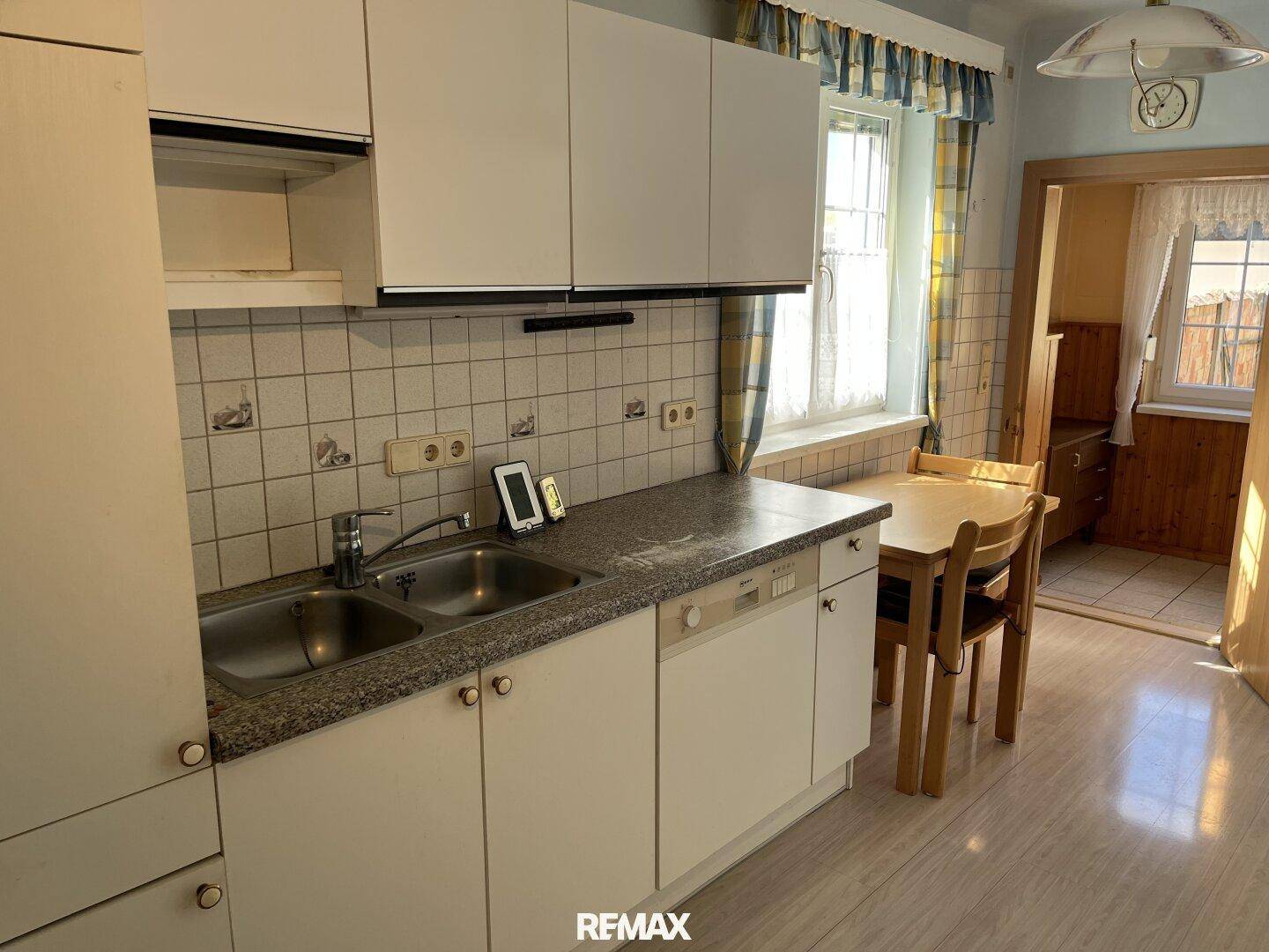 Funktionale Küche mit weißen Schränken, Granitarbeitsplatte und Essbereich am Fenster.