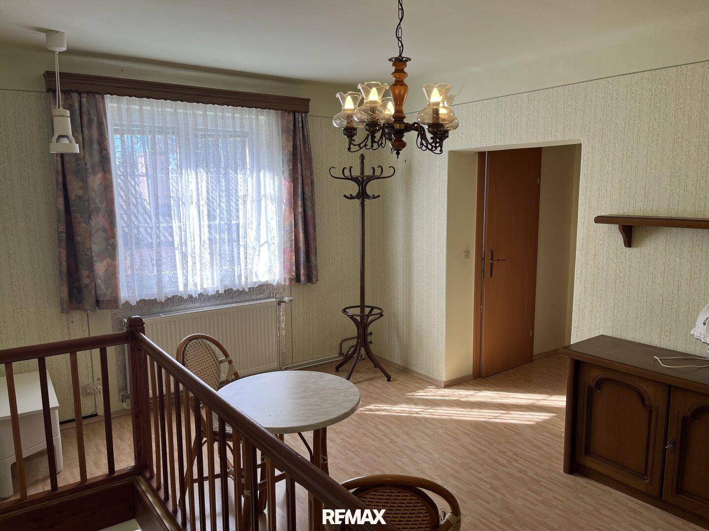 Heller Flur im Obergeschoss mit kleinem Tisch, Garderobe und Blick aus dem Fenster.
