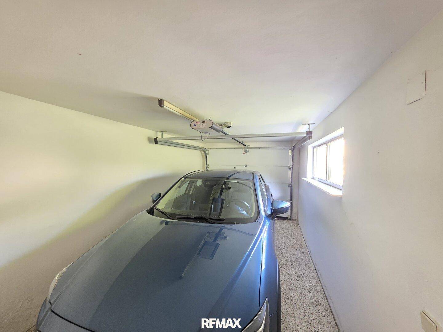 Geräumige Garage mit einem geparkten Auto und einem Fenster für Tageslicht.