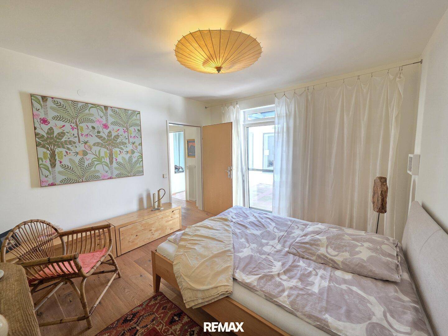 Gemütliches Schlafzimmer mit Holzfußboden, Doppelbett und Zugang zu einem Außenbereich.
