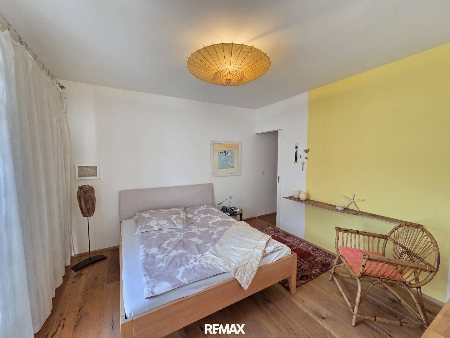 Helles Schlafzimmer mit Holzfußboden, Doppelbett und einer farbigen Akzentwand.