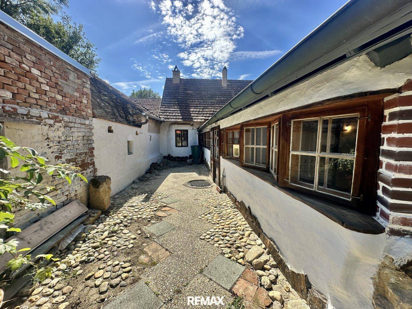 Historischer Innenhof mit Kopfsteinpflaster und alten Ziegelmauern, umgeben von Gebäuden.