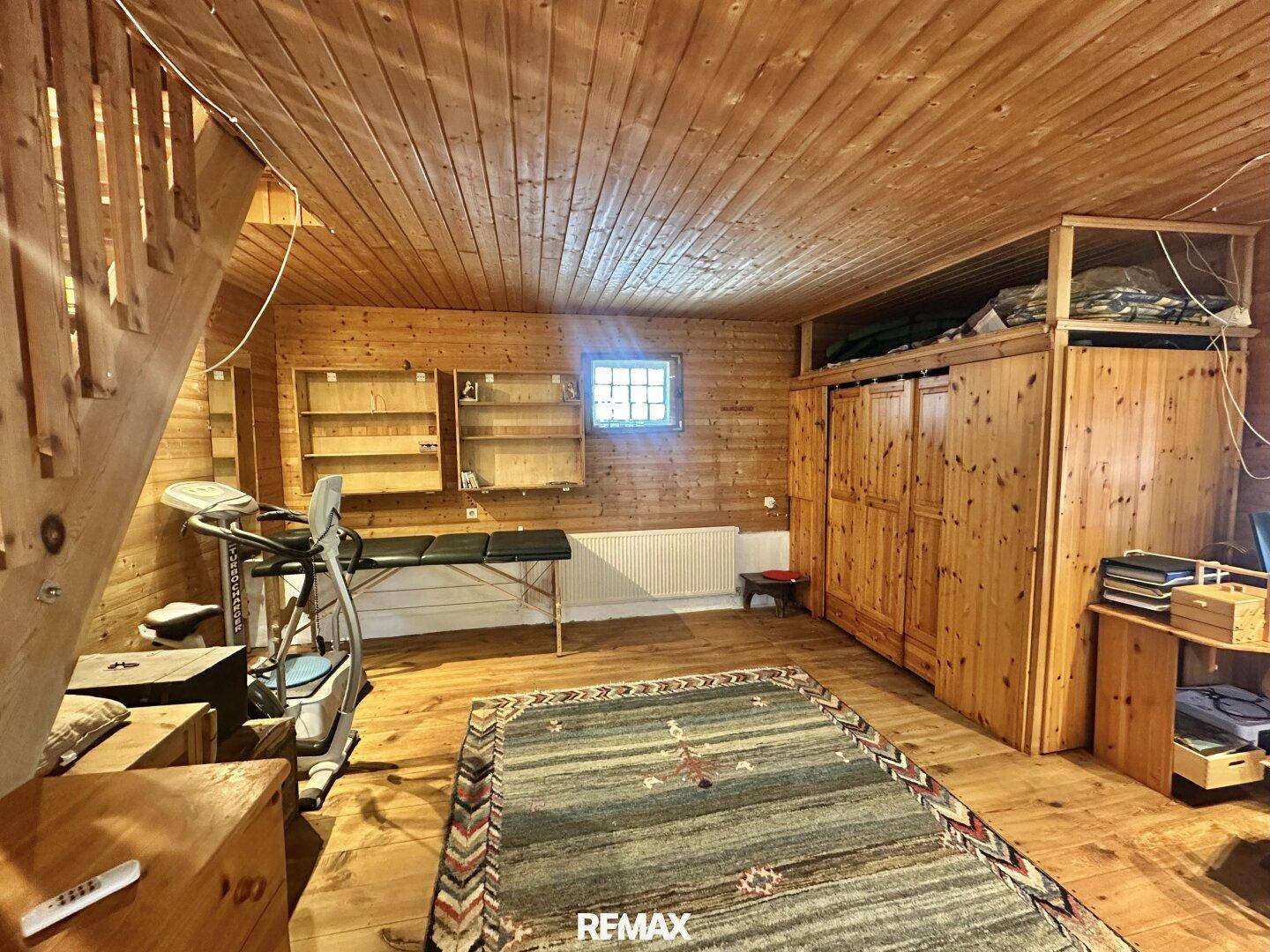 Vielseitiger Raum mit Holzvertäfelung, Holzboden und Fitnessgeräten, ideal für Sport oder Hobby.