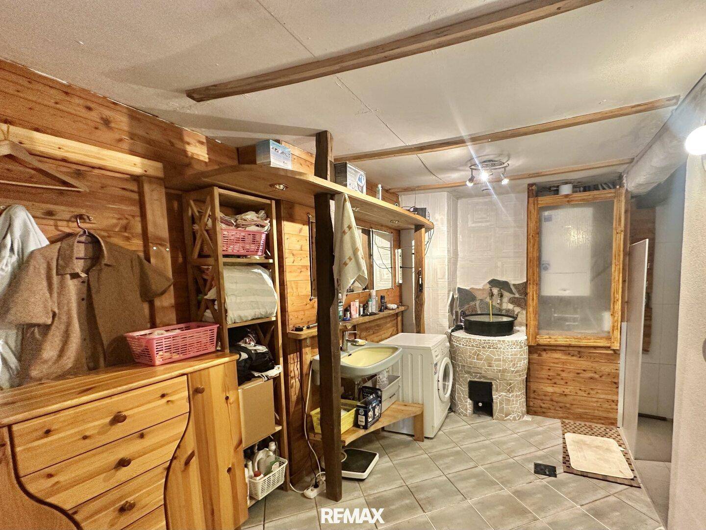 Praktischer Hauswirtschaftsraum mit Waschmaschine, Spülbecken und Holzregalen für Stauraum.