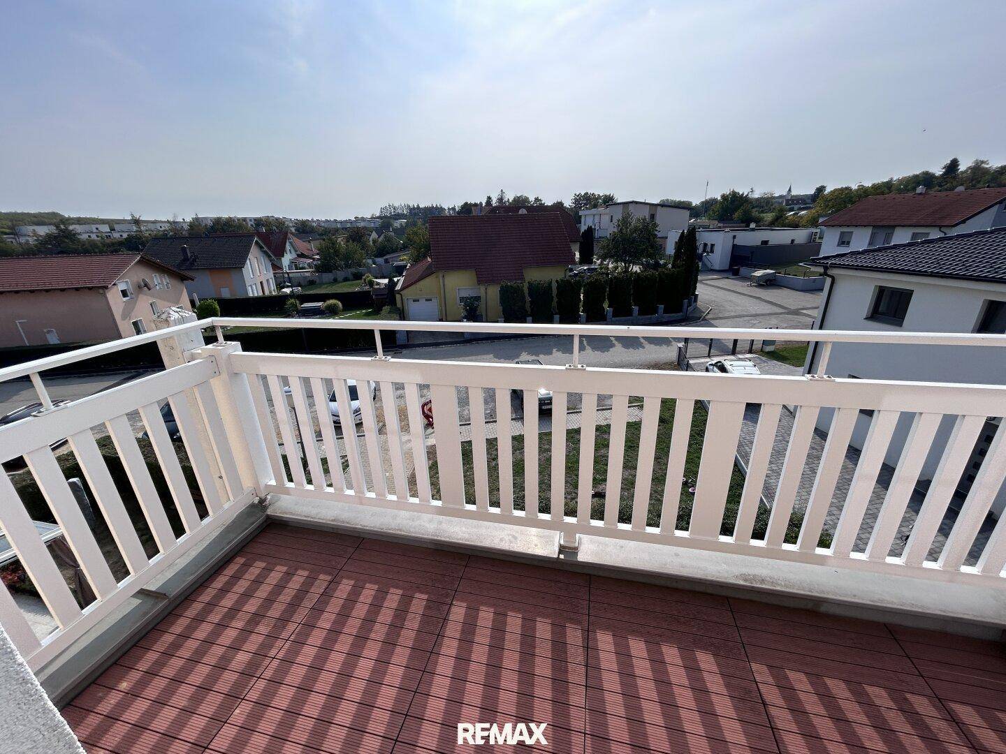 Heller Balkon mit robustem Bodenbelag und weißem Geländer, ideal für entspannte Stunden im Freien.