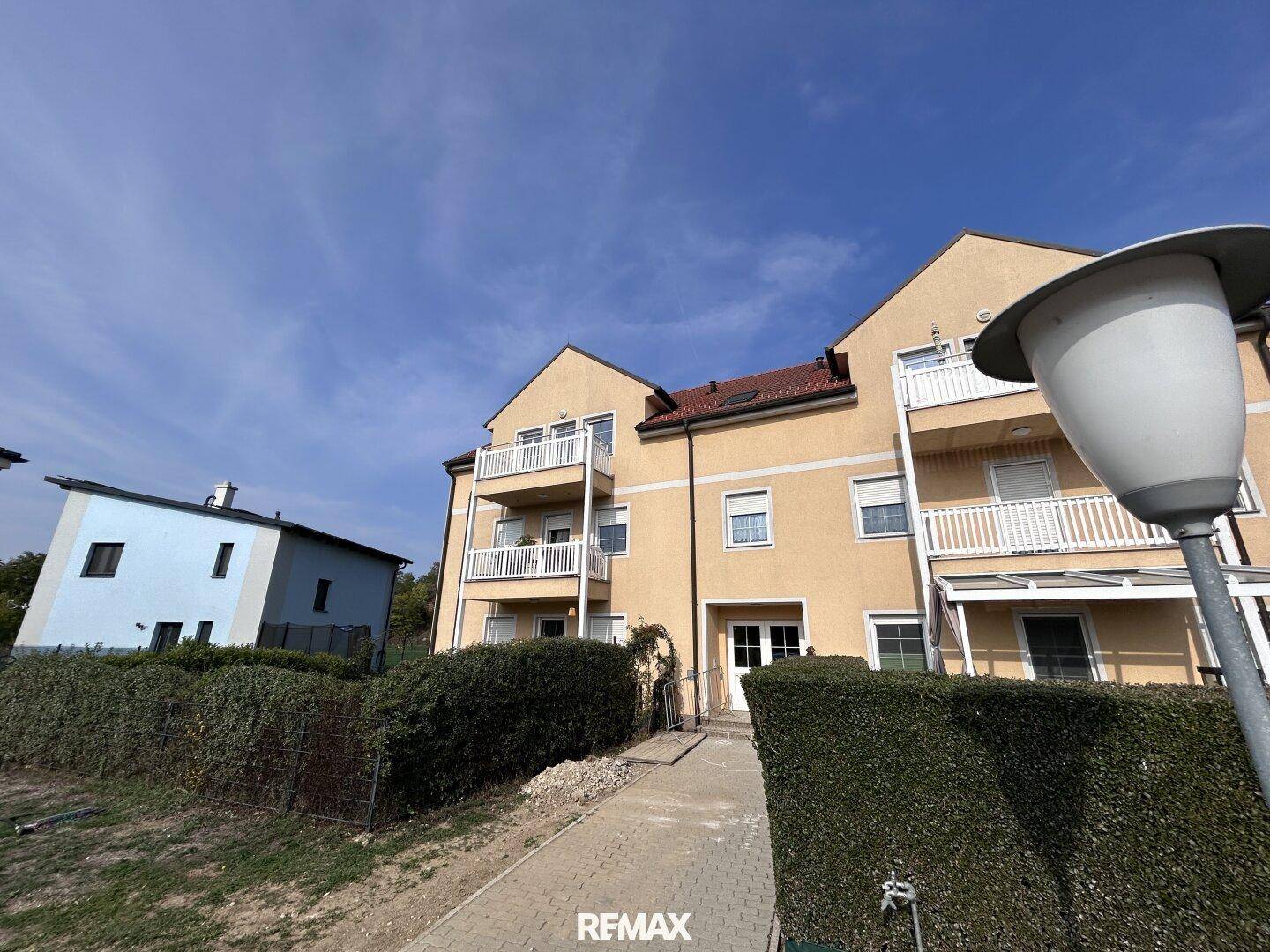 Mehrstöckiges Wohngebäude mit Balkonen und gepflegter Hecke, umgeben von einer ruhigen Wohngegend.