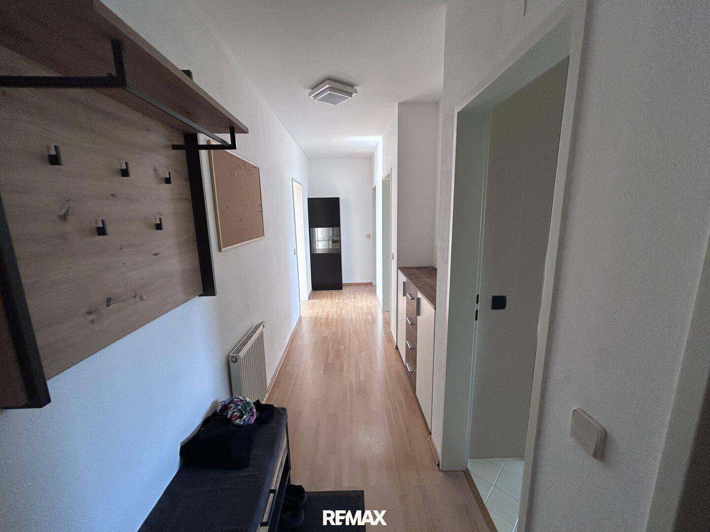 Heller Flur mit Holzfußboden, Garderobe und praktischen Einbauschränken für zusätzlichen Stauraum.
