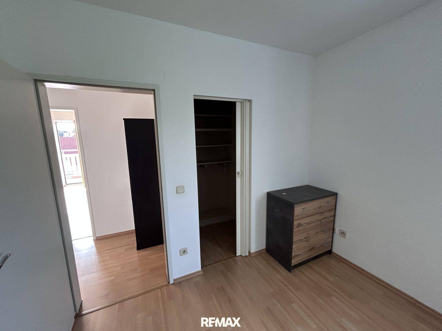 Zimmer mit Holzfußboden und Zugang zu einem begehbaren Kleiderschrank, bietet vielseitige Nutzungsmöglichkeiten.
