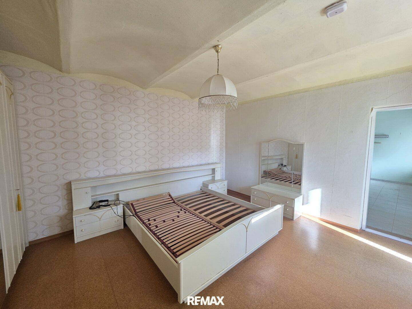 Schlafzimmer mit Doppelbettrahmen, Nachttischen und einem Schminktisch mit Spiegel.