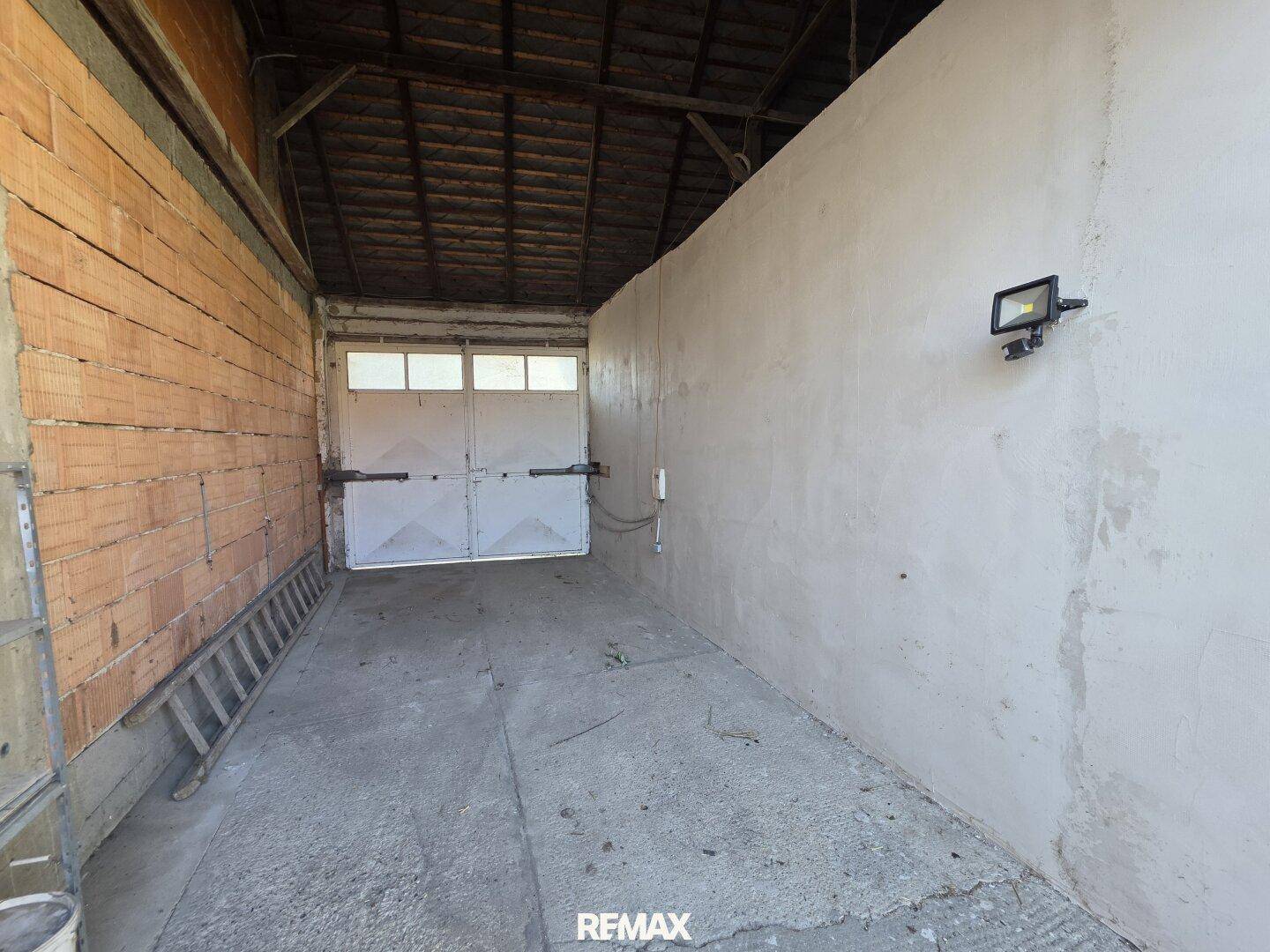 Geräumige Garage mit Betonboden und Holzdachkonstruktion, ideal für Fahrzeuge oder Lagerung.