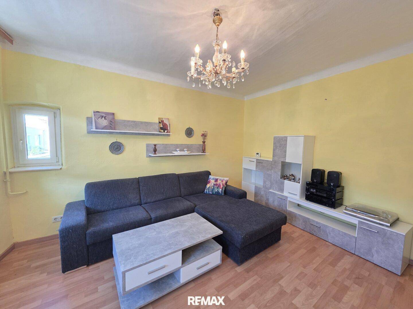 Gemütliches Wohnzimmer mit Ecksofa, Couchtisch und dekorativen Wandregalen.