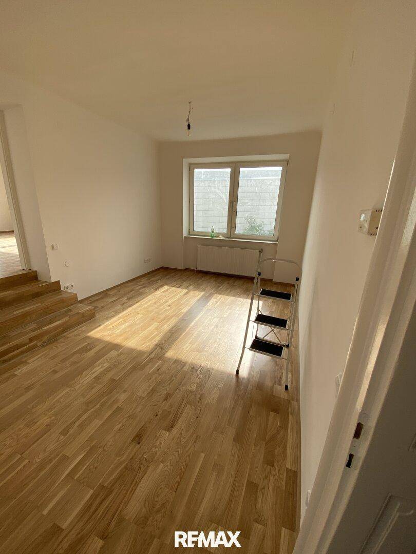 Heller Raum mit neuem Parkettboden und einem Fenster, das viel Tageslicht hereinlässt.