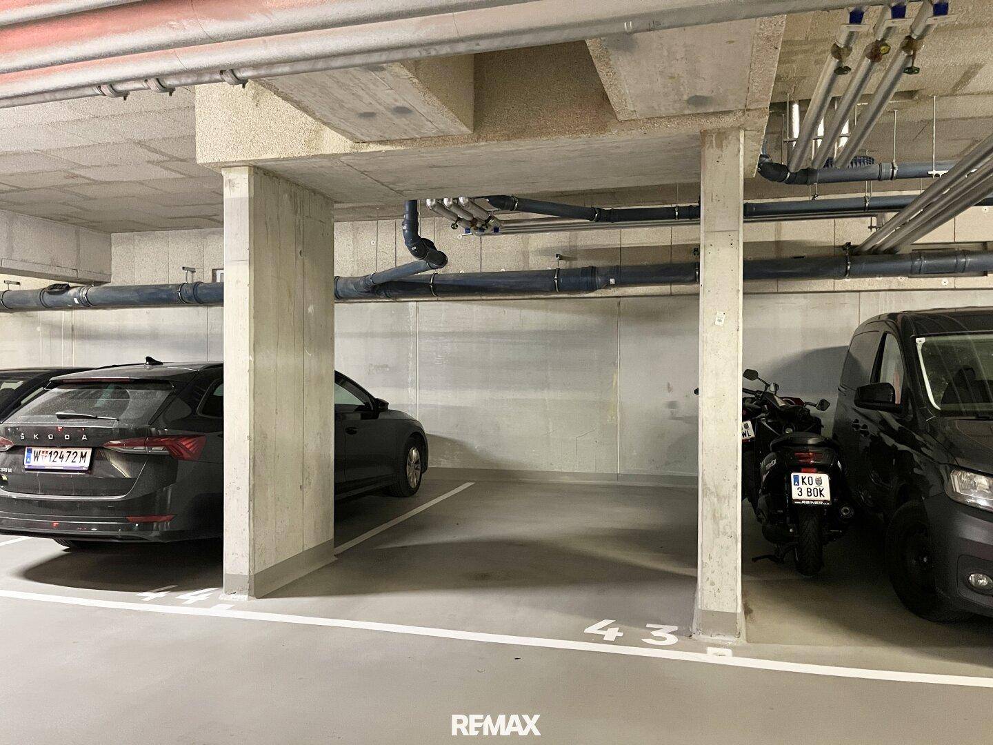 Tiefgarage mit mehreren Stellplätzen für Autos und Motorräder.