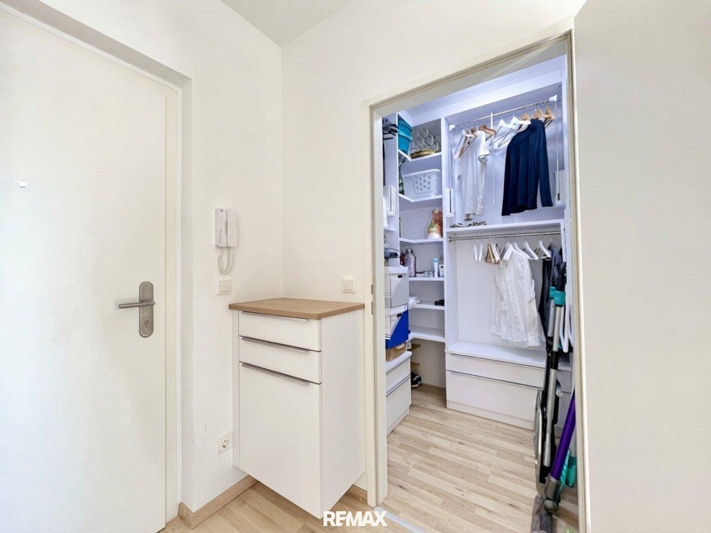 Heller Eingangsbereich mit praktischem Einbauschrank und offenem begehbarem Kleiderschrank.