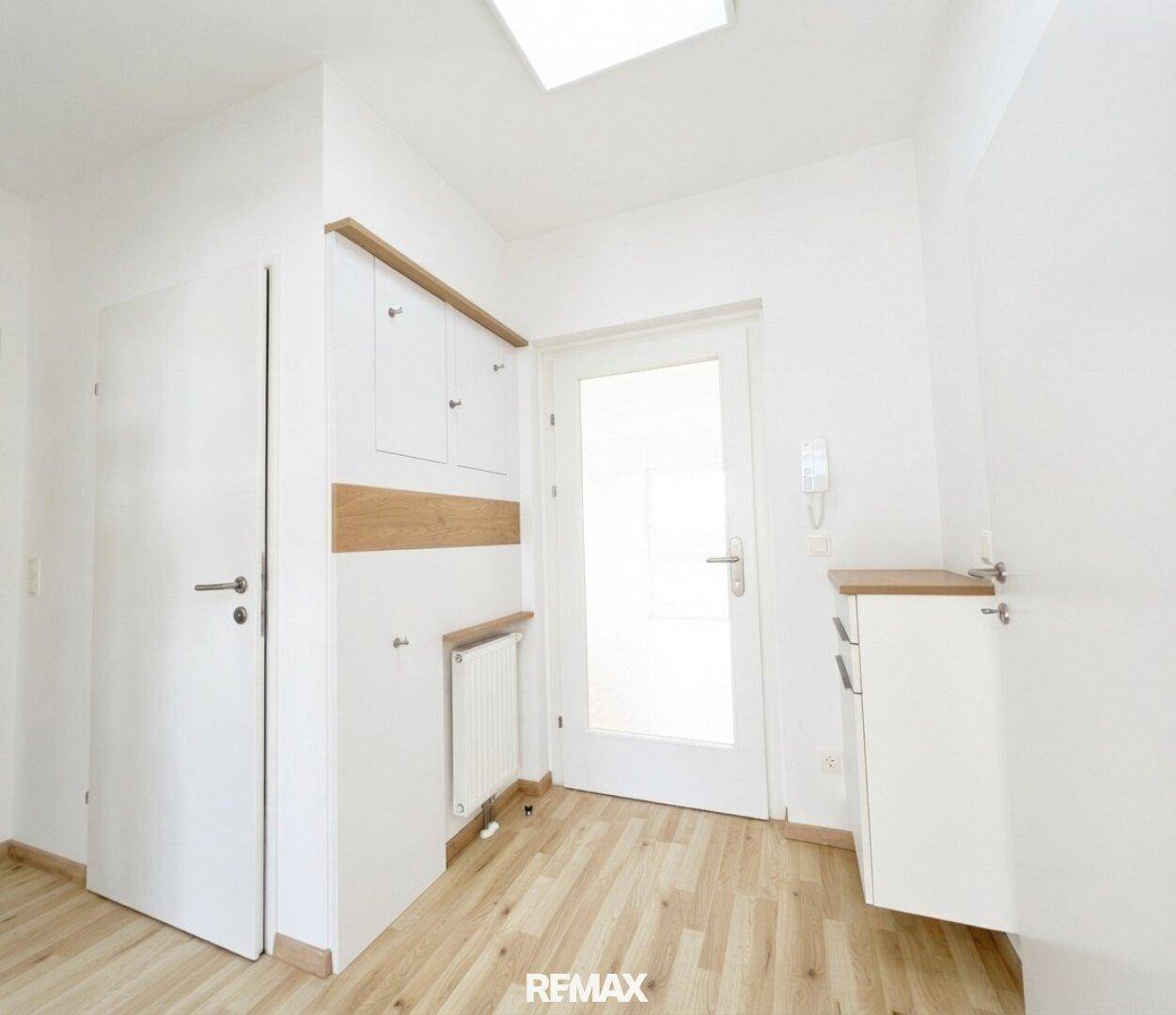 Heller Flur mit integrierten Schränken, Heizkörper und Zugang zur Wohnung.