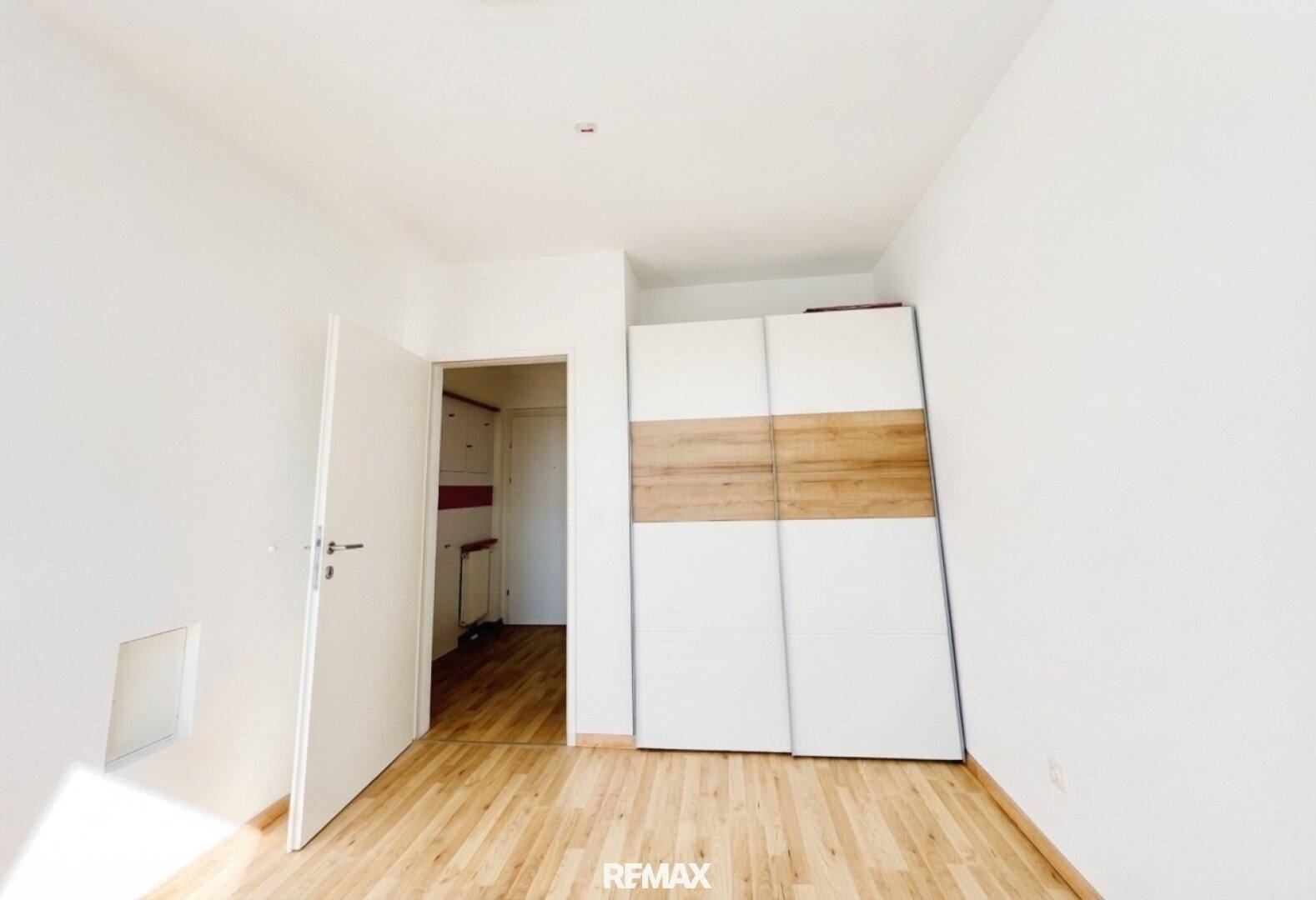 Geräumiges Zimmer mit hellem Holzboden und großem Einbauschrank mit Schiebetüren.