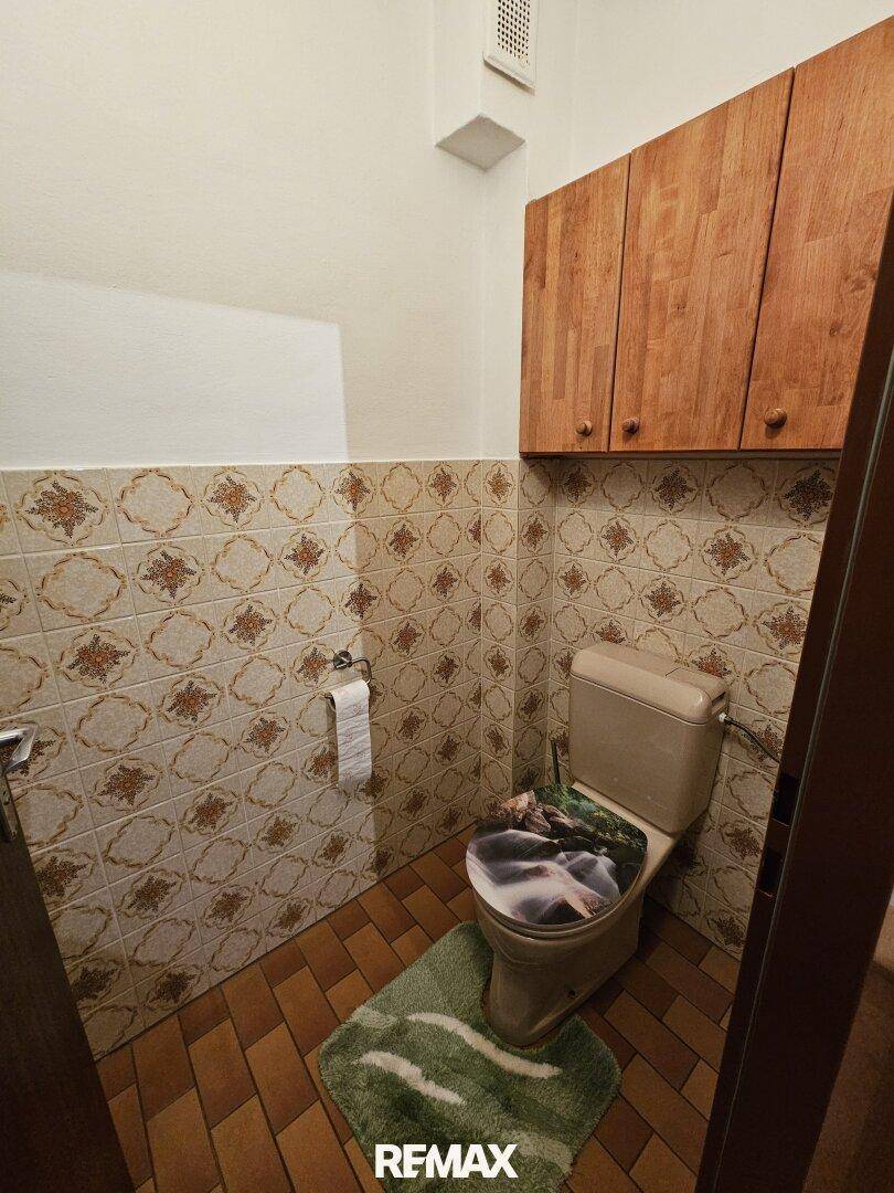 Separate Toilette mit traditionellen Fliesen und einem kleinen Holzschrank.
