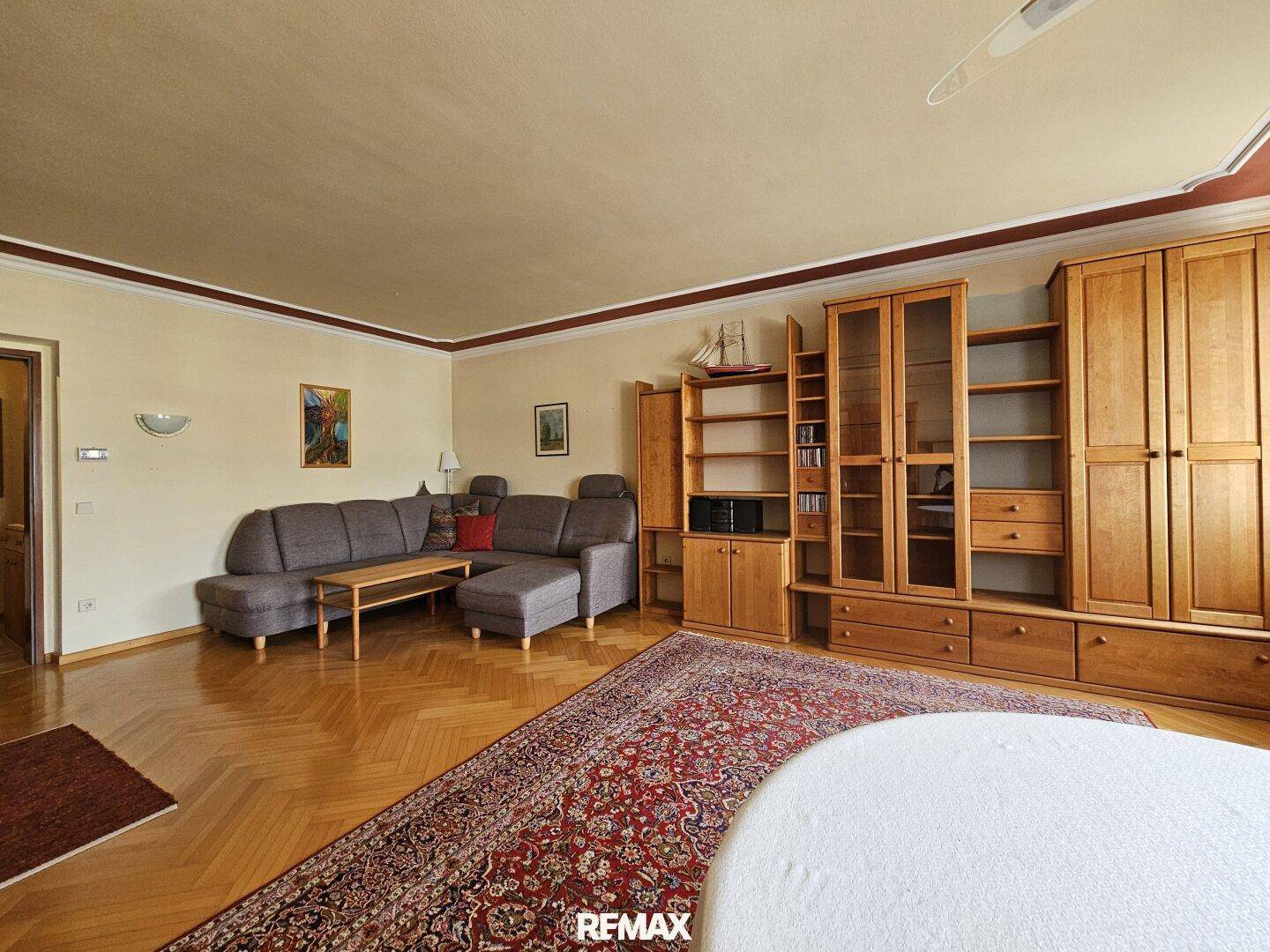 Wohnzimmer mit gemütlicher Sitzecke, Holzschränken und einem traditionellen Orientteppich.