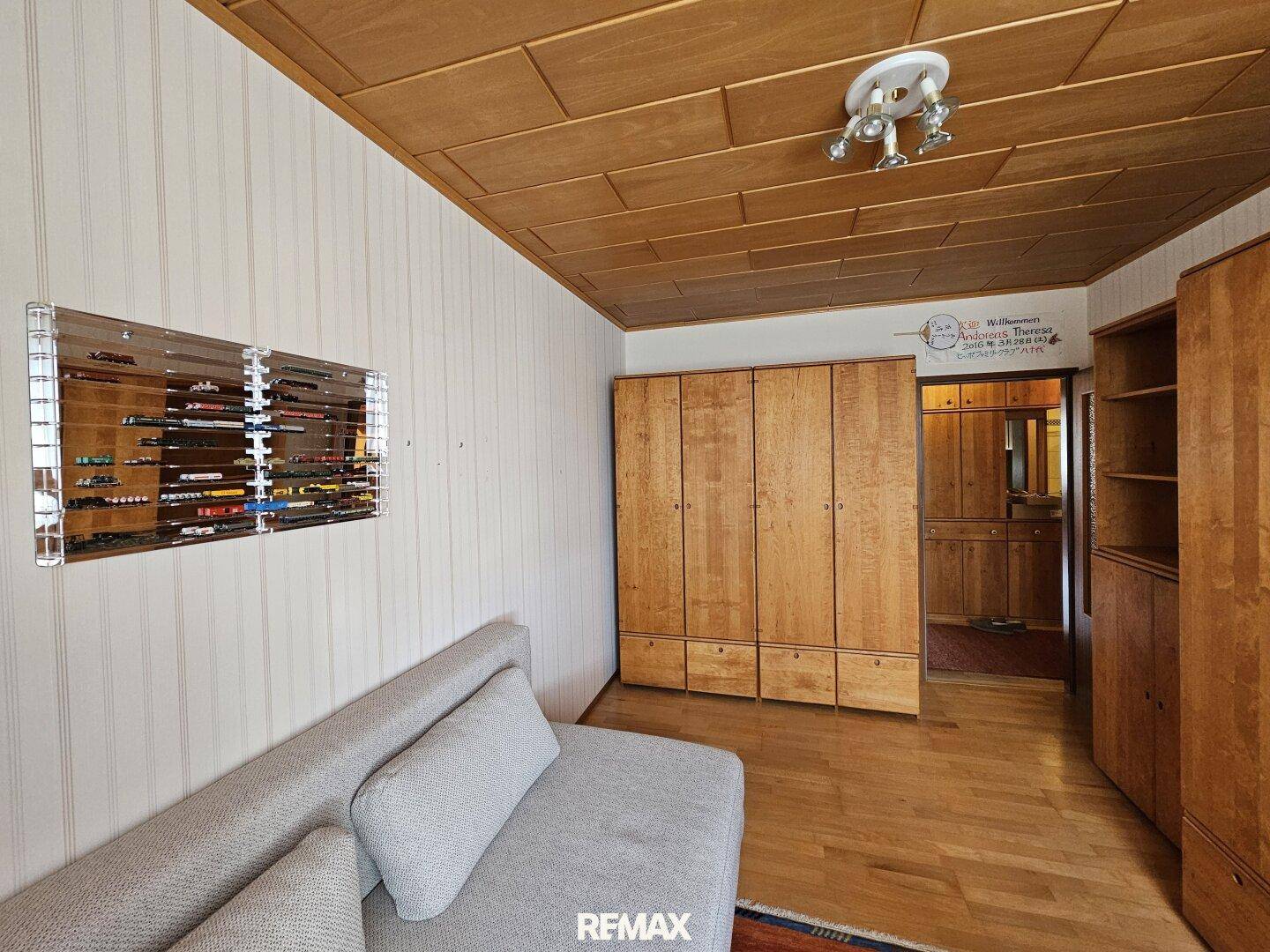 Zimmer mit Holzdecke, Sofa und großem Kleiderschrank, ideal als Gäste- oder Arbeitszimmer.