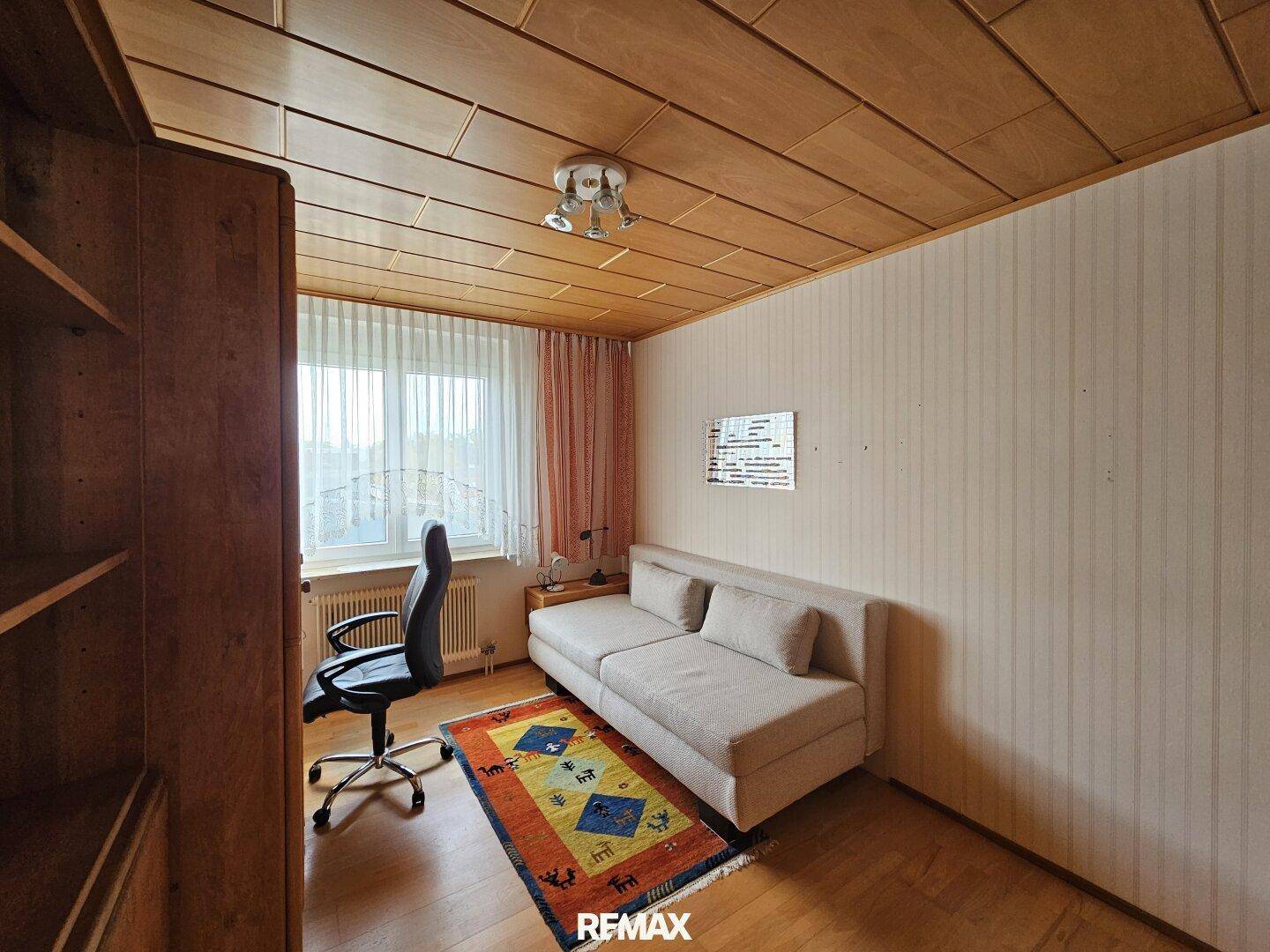 Arbeitszimmer mit Holzdecke, Schreibtisch und Sofa, bietet eine ruhige Arbeitsumgebung.