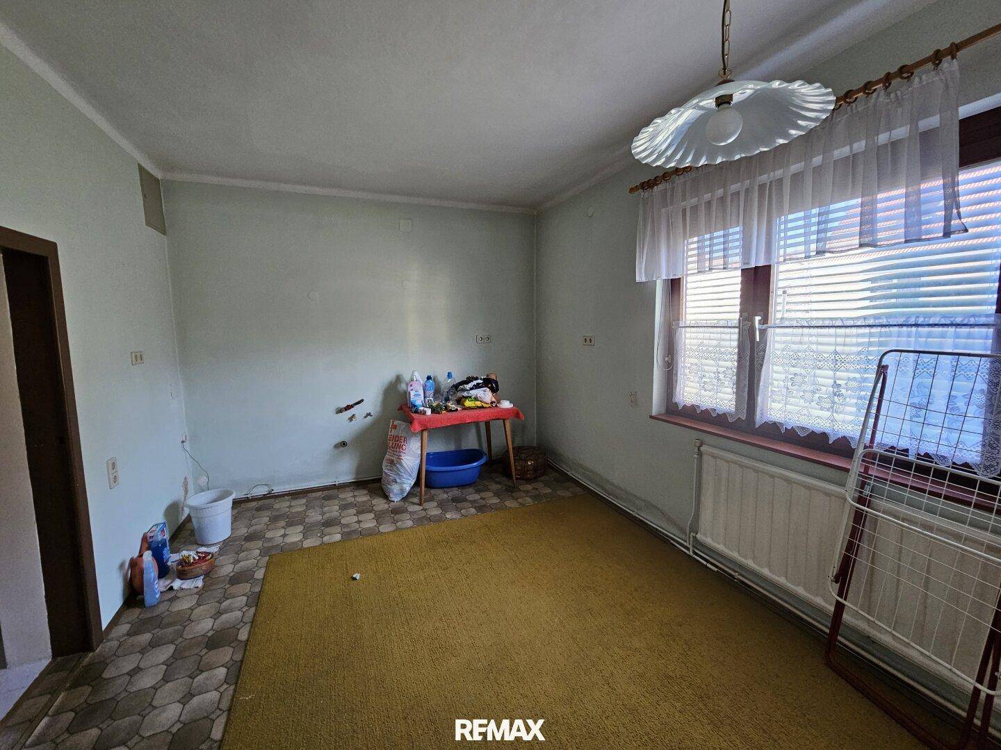 Geräumiger Raum mit Teppichboden, Fenster und Heizkörper, bereit zur Renovierung.
