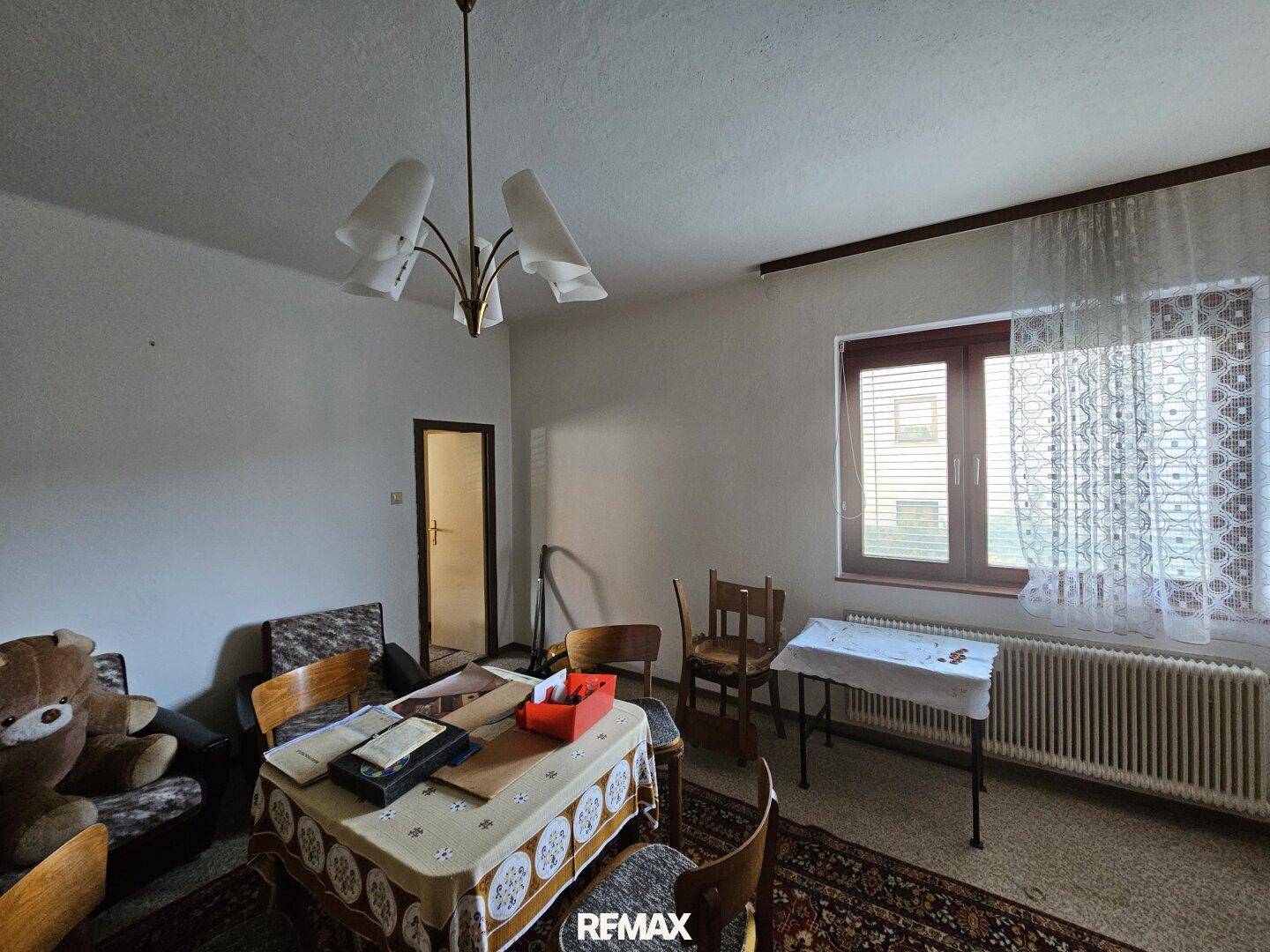 Wohnzimmer mit Esstisch, Sofa, Teppichboden und großem Fenster.